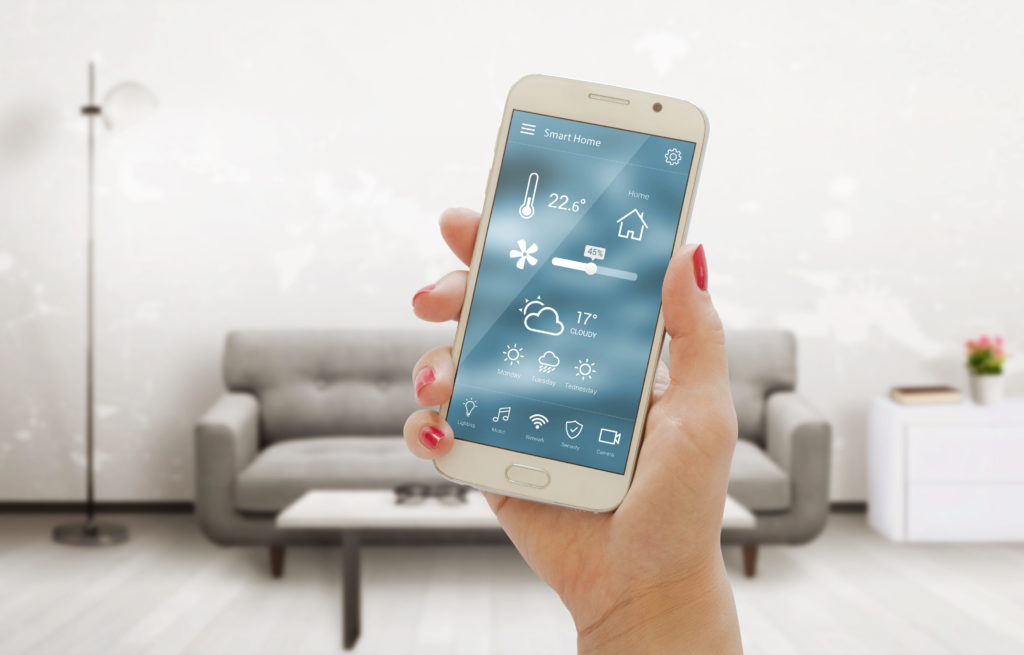 手持智能手机在客厅中使用恒温器应用程序